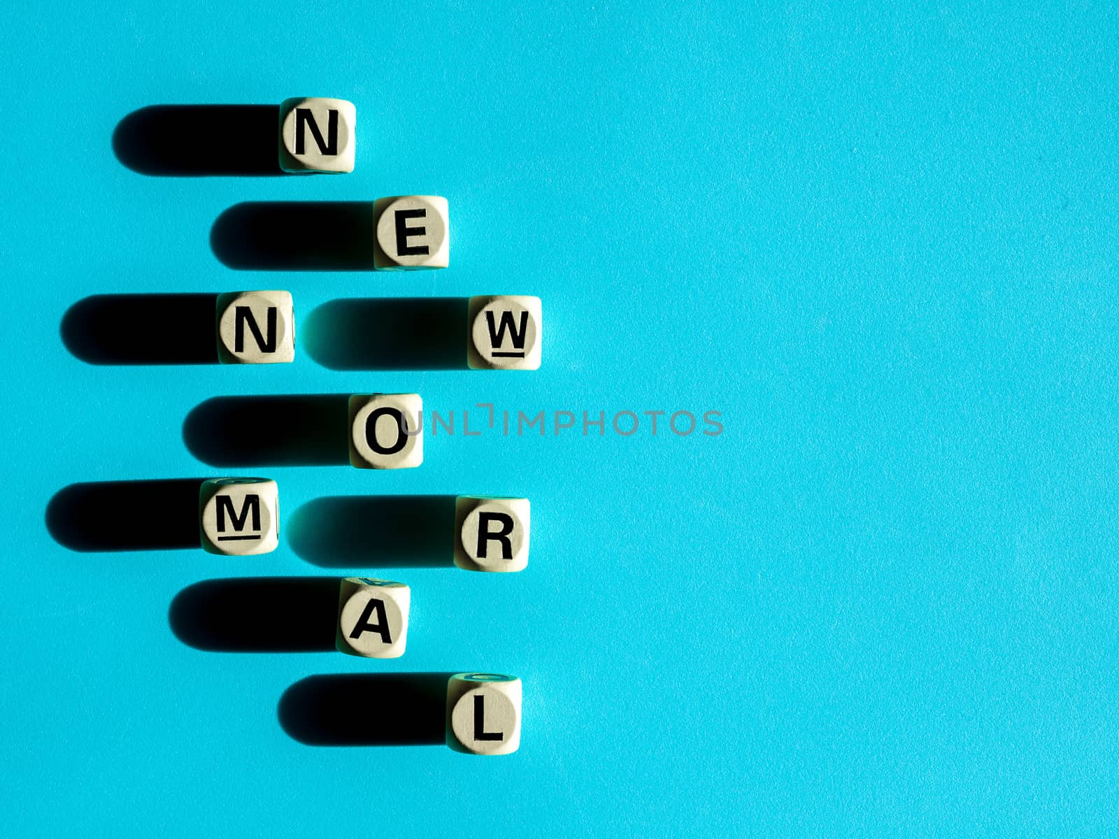 NEW NORMAL, word on wooden alphabet cube on blue background with copy space, top view, minimal style. New normal after covid-19 pandemic with social distancing concept.