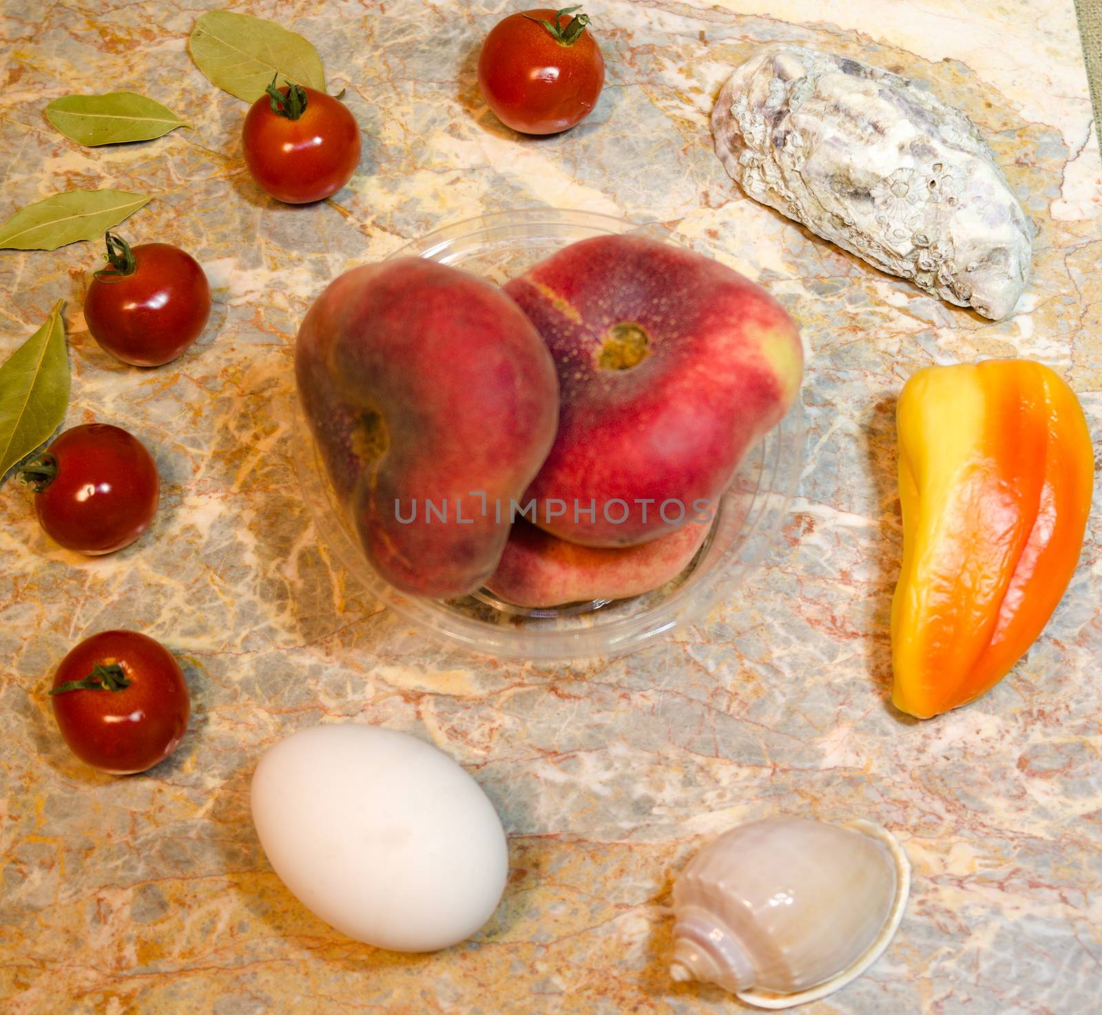 vegetables, fruits, seashells and peaches on a marble surface: cherry tomatoes, bell peppers, bay leaves, oyster, seashell, fig peaches and a chicken egg