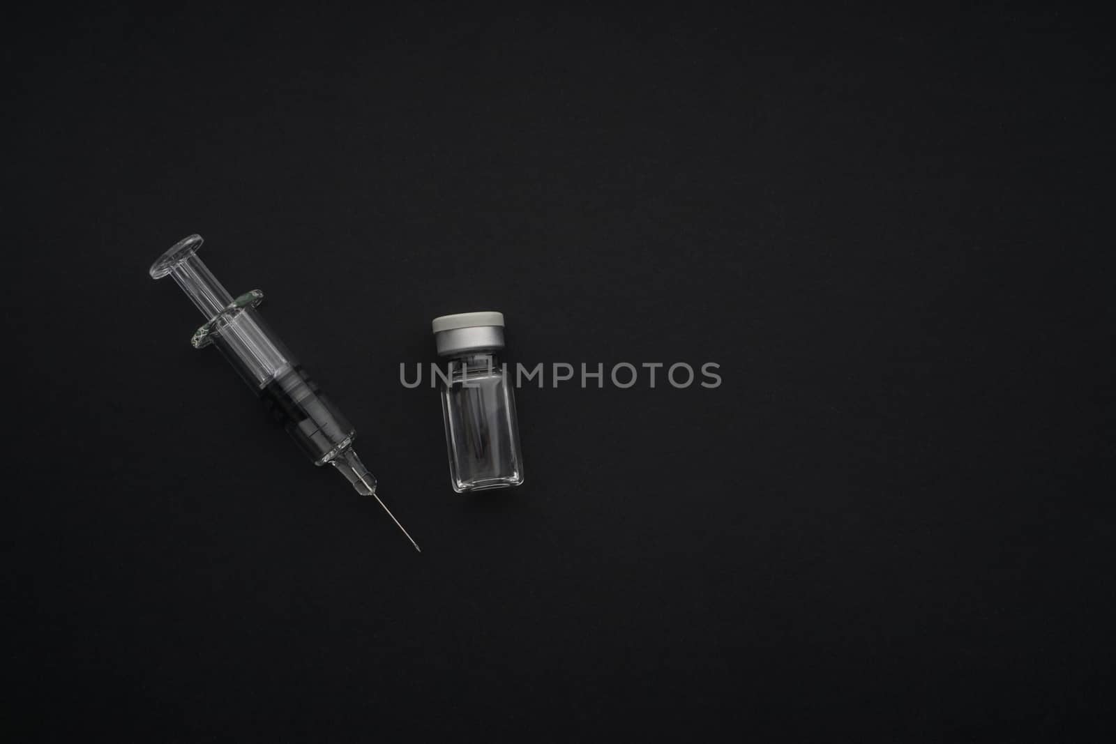 Closeup syringe and vials on black background. Healthcare dan Copy Space concept