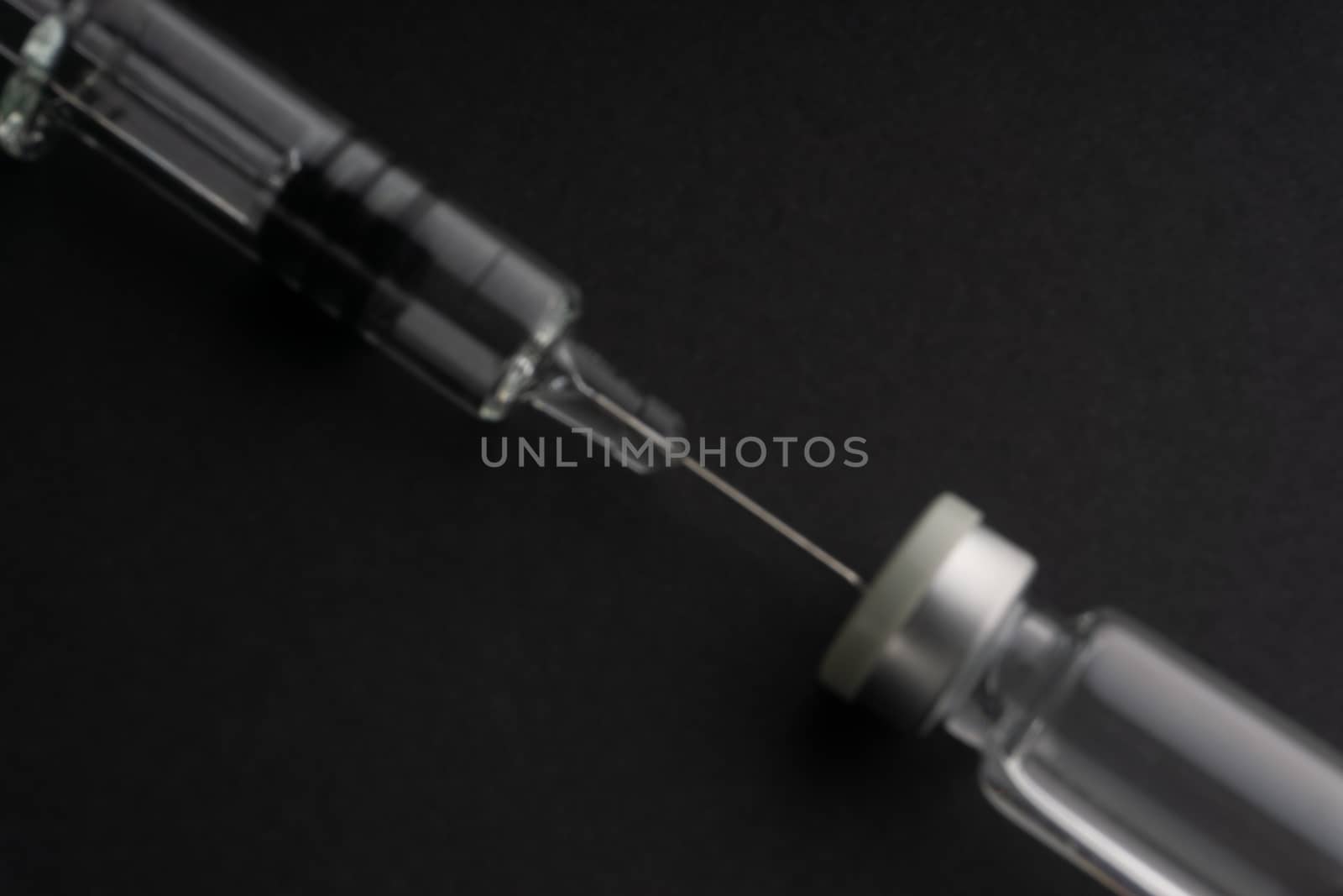 Closeup blurry image of syringe and vials on black background. Healthcare dan Copy Space concept