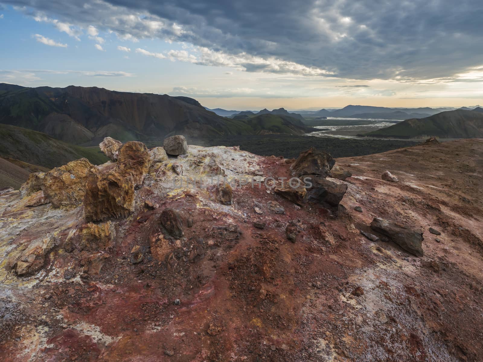 Colorful rhyolit red and orange fumarole at foot of Brennisteinsalda mountain with panorma of Landmannalaugar. Area of Fjallabak Nature Reserve in Highlands of Iceland.