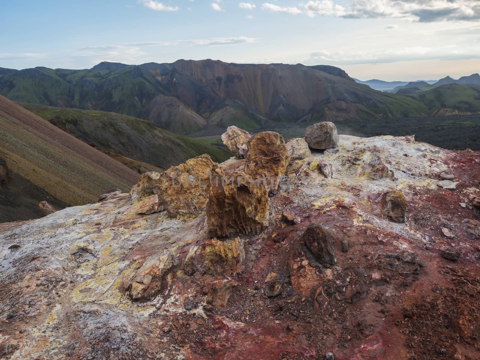 Colorful rhyolit red and orange fumarole at foot of Brennisteinsalda mountain with panorma of Landmannalaugar. Area of Fjallabak Nature Reserve in Highlands of Iceland.