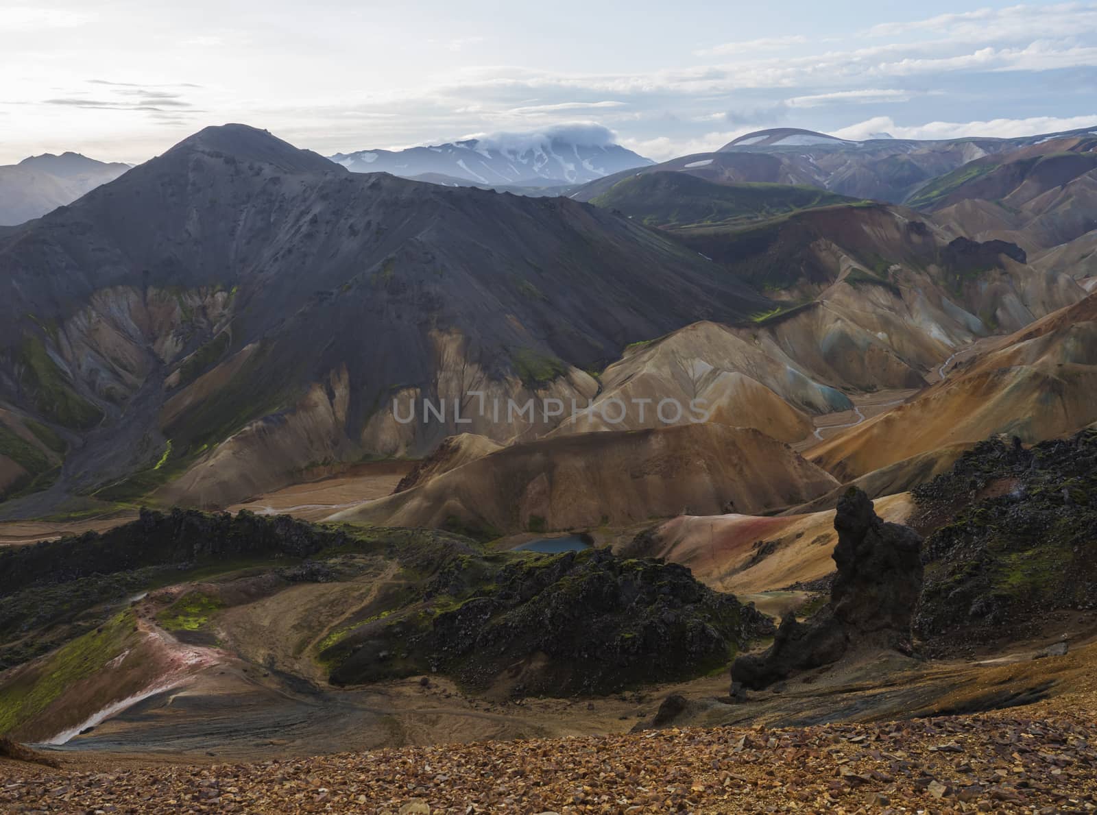 Colorful Rhyolit rainbow mountain panorma with multicolored volcanos and geothermal lake and snow covered peaks. Sunrise in Landmannalaugar at Fjallabak Nature Reserve, Highlands Iceland.