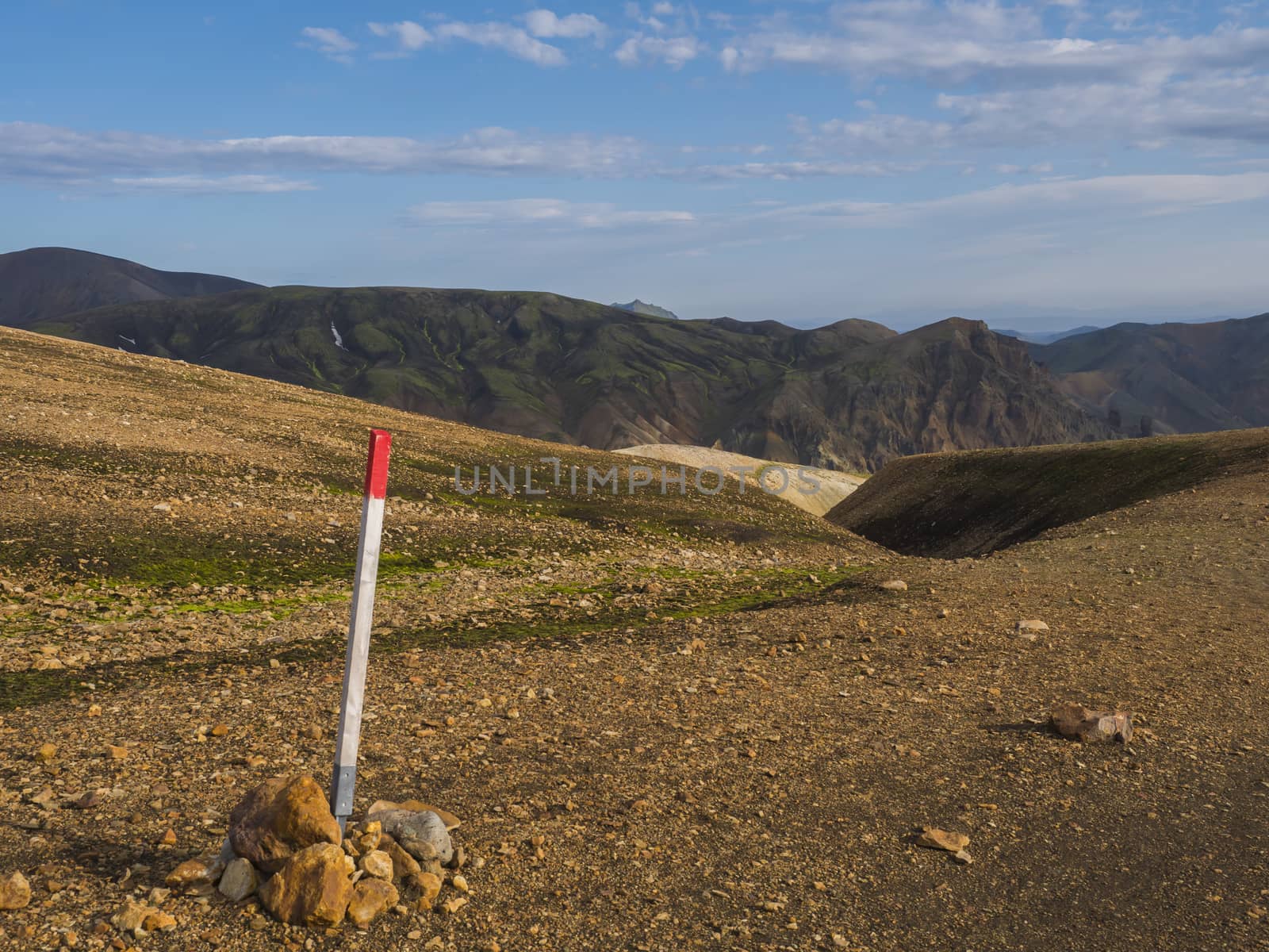 Red mark on trail sign pole on famous Laugavegur hiking trail with Colorful Rhyolit Landmannalaugar mountain at Fjallabak Nature Reserve in Highlands of Iceland.