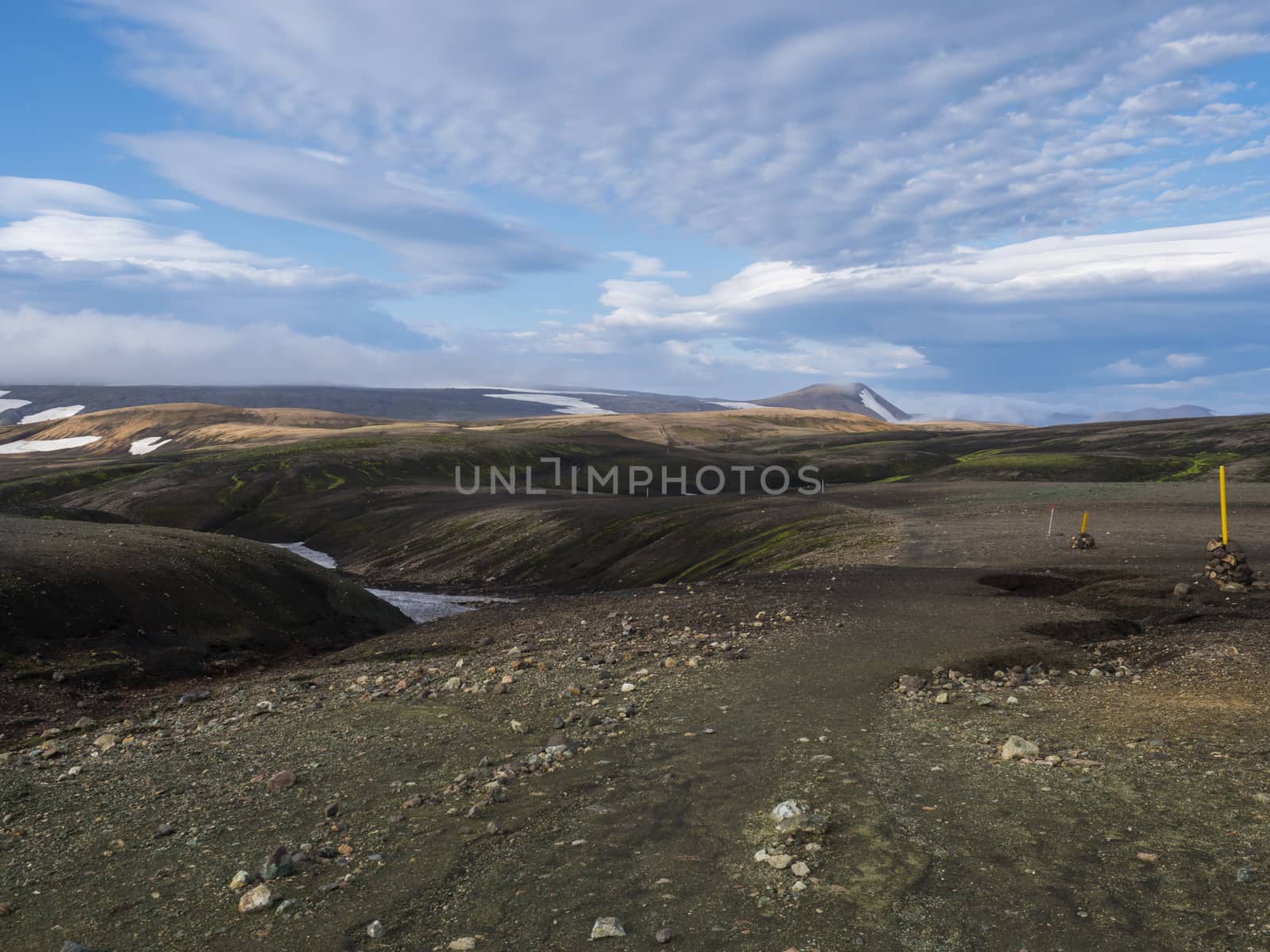 view on hiking path Laugavegur trail at Rhyolit Landmannalaugar mountain with snow fiields and multicolored volcanos at Fjallabak Nature Reserve in Highlands of Iceland.