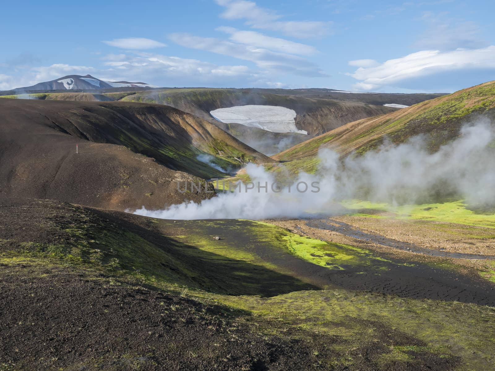 Landmannalaugar colorful Rhyolit mountains with steam from hot spring on famous Laugavegur trek. Fjallabak Nature Reserve in Highlands of Iceland, summer blue sky