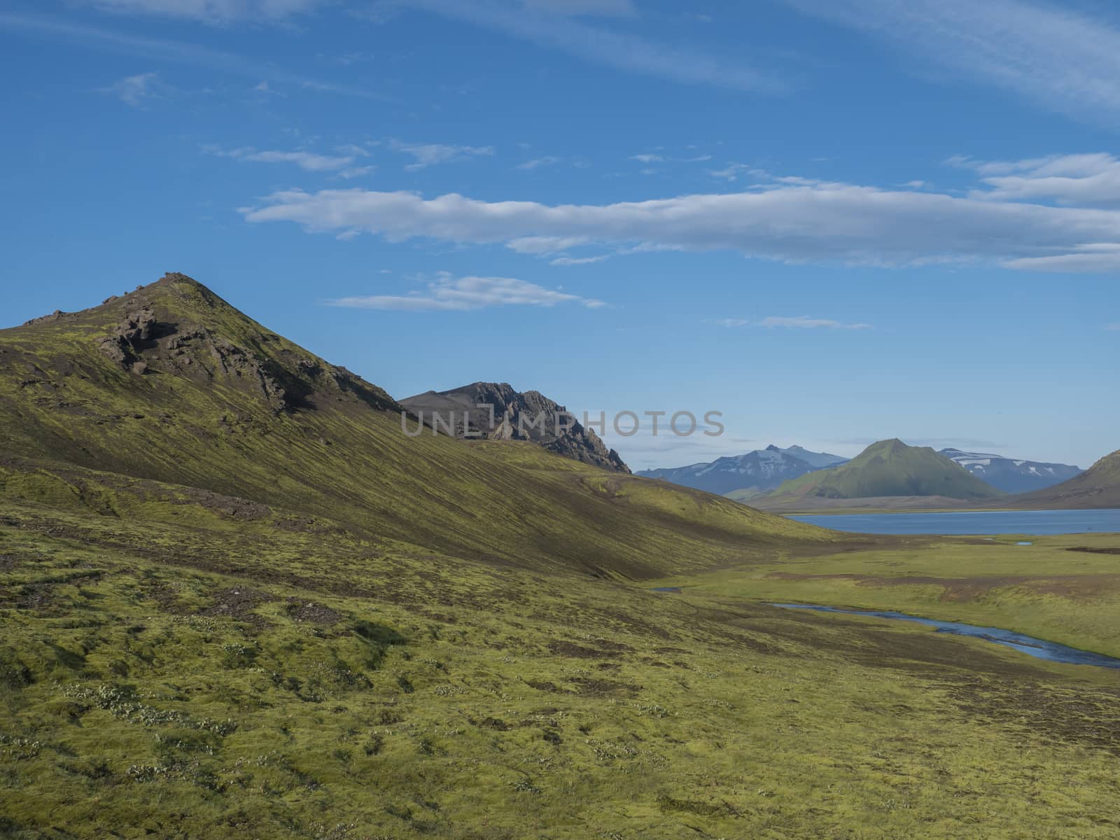 Beautiful landscape of blue Alftavatn lake and river with snow covered mountains and green hills and blue sky background. Summer landscape of the Fjallabak Nature Reserve in the Highlands of Iceland. Copy space