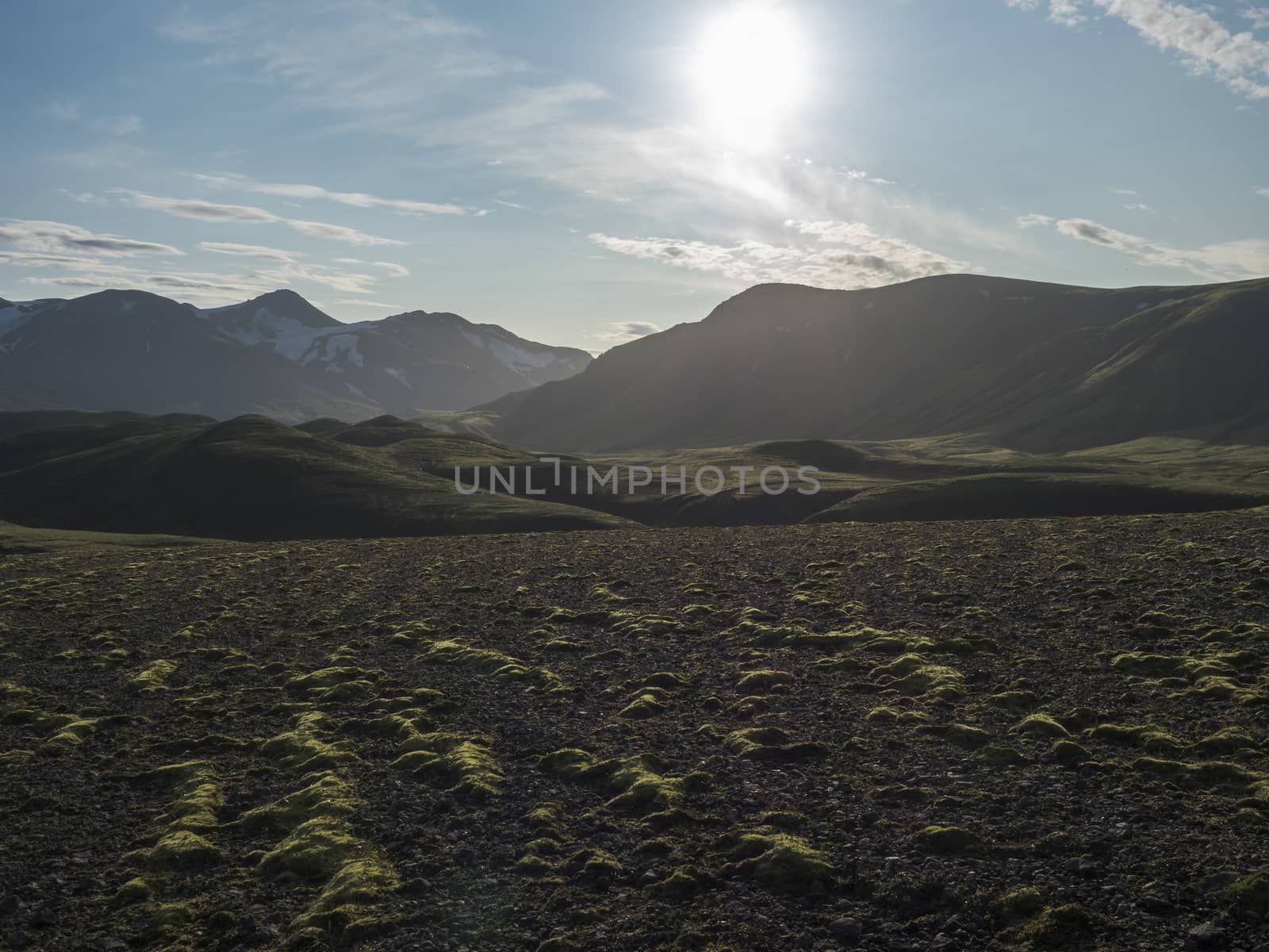 Volcanic landscape with snow covered mountains, green hills and lava gravel ground covered by lush moss. Fjallabak Nature Reserve in the Highlands of Iceland.