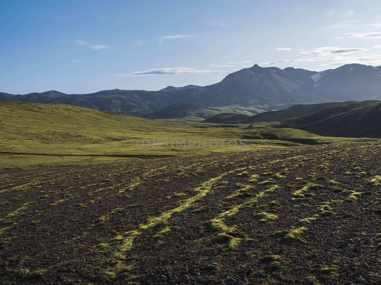 Volcanic landscape with snow covered mountains, green hills and lava gravel ground covered by lush moss. Fjallabak Nature Reserve in the Highlands of Iceland.