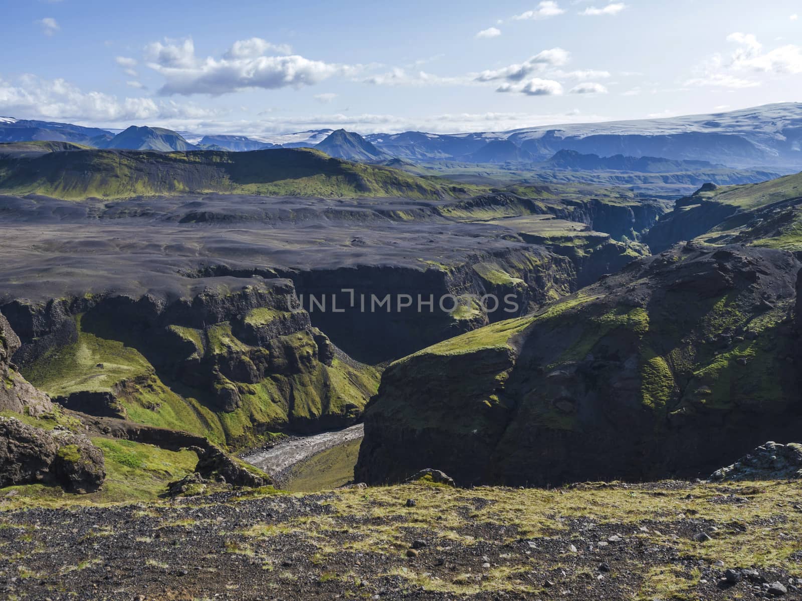 View on majestic Markarfljotsgljufur Canyon gorge, river and Tindfjallajokull glacier tongue and green hills. Fjallabak Nature Reserve, Iceland. Summer blue sky, clouds