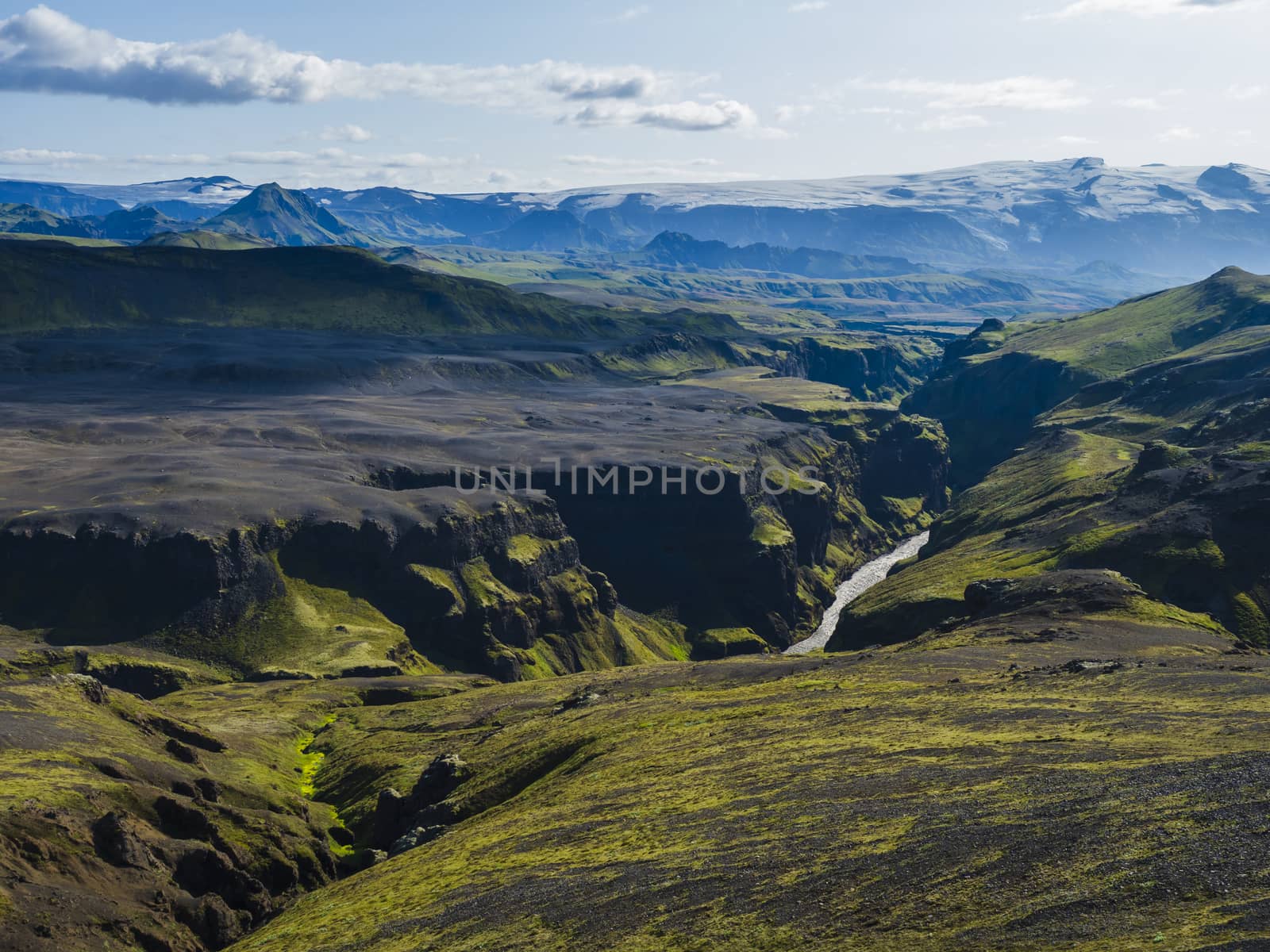View on majestic Markarfljotsgljufur Canyon gorge, river and Tindfjallajokull glacier tongue and green hills. Fjallabak Nature Reserve, Iceland. Summer blue sky, clouds