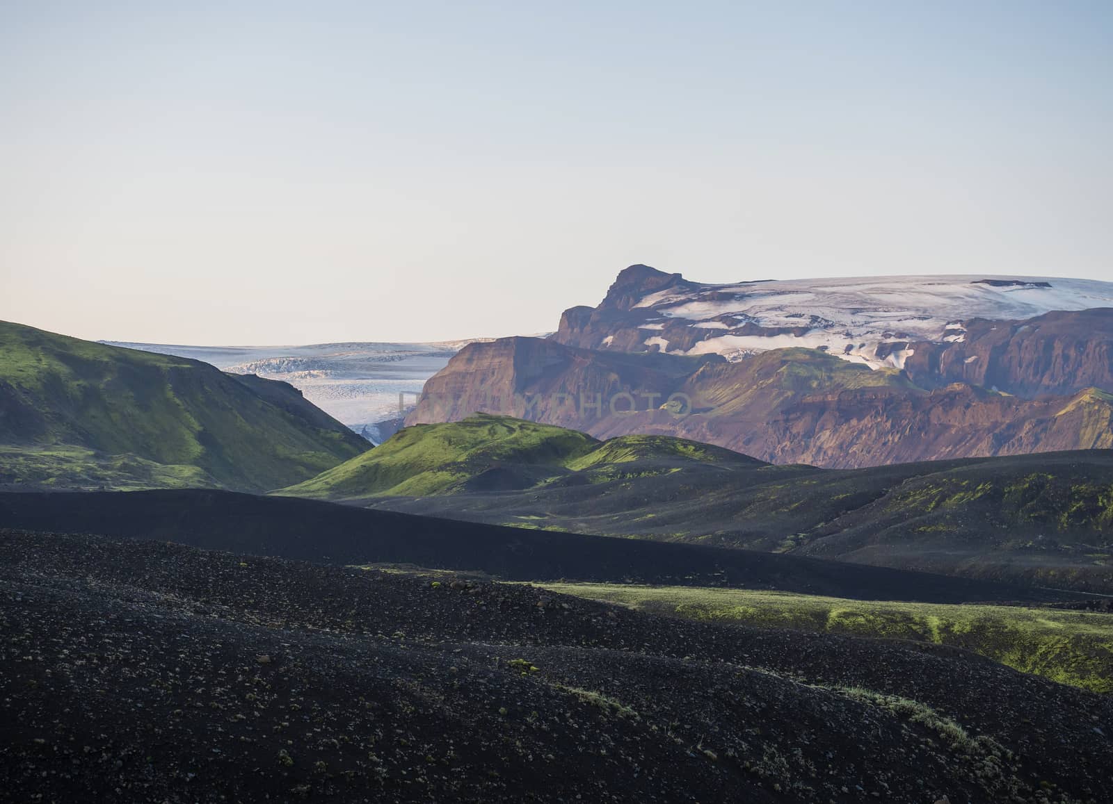 Sunrise at Botnar campsite at Iceland on Laugavegur hiking trail, green valley in volcanic landscape with view on Myrdalsjokull glacier. Early morning pink light.