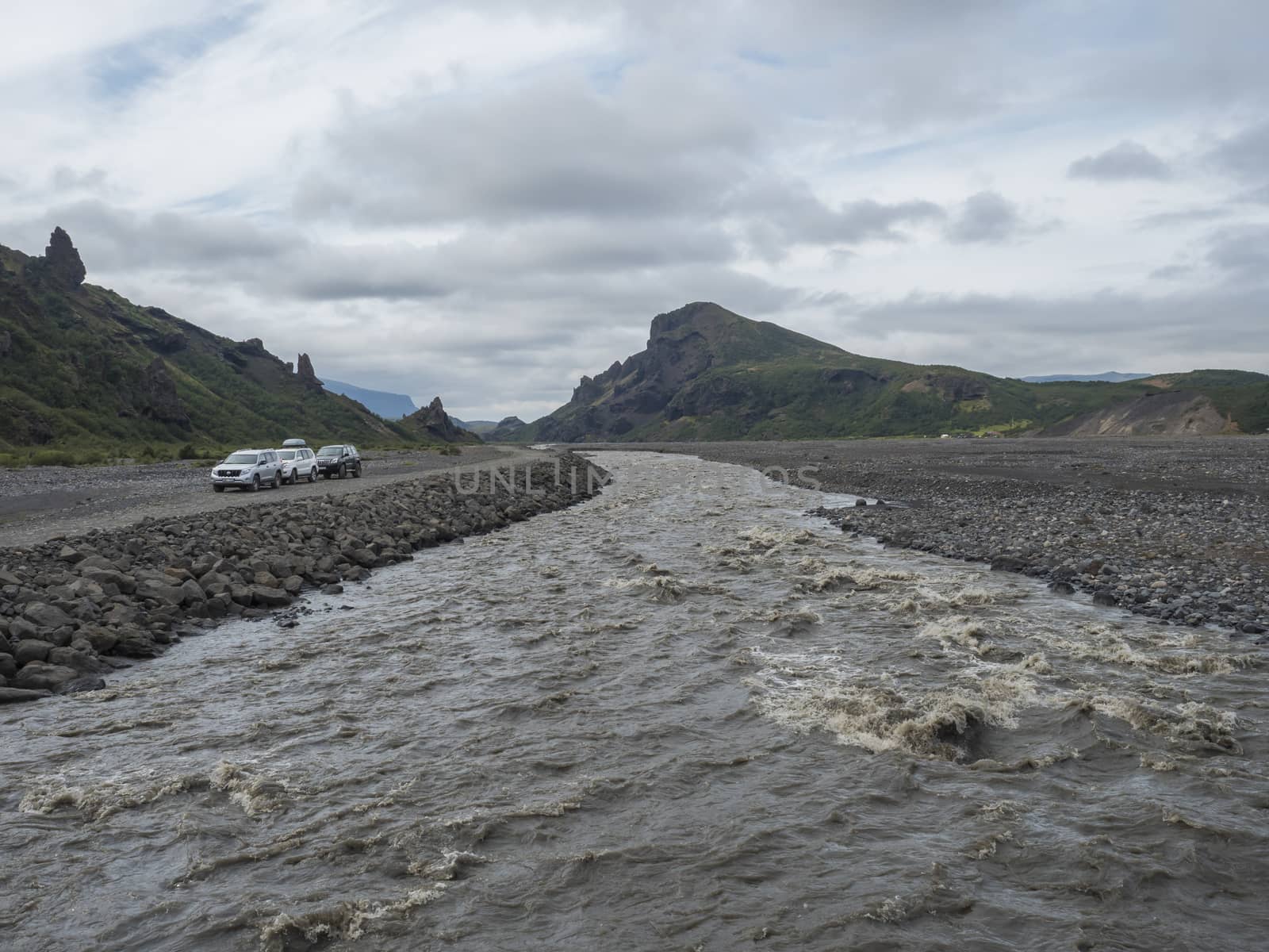ICELAND, THORSMORK, August 3, 2019: view on glacier wild river Krossa and green sharp volanic hills from footbridge border of Thorsmork and Godaland.