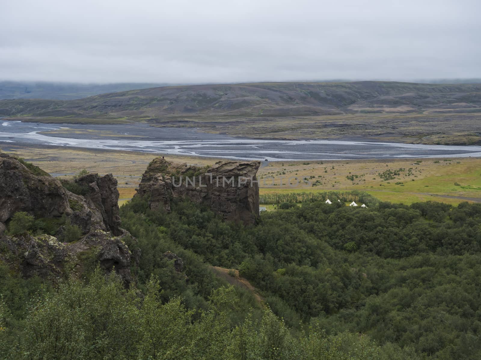 Landscape of green valley of Thorsmork with volcano huts camp site, sharp green rocks, river Krossa delta and green forest. Foggy summer day, Highlands of Iceland.