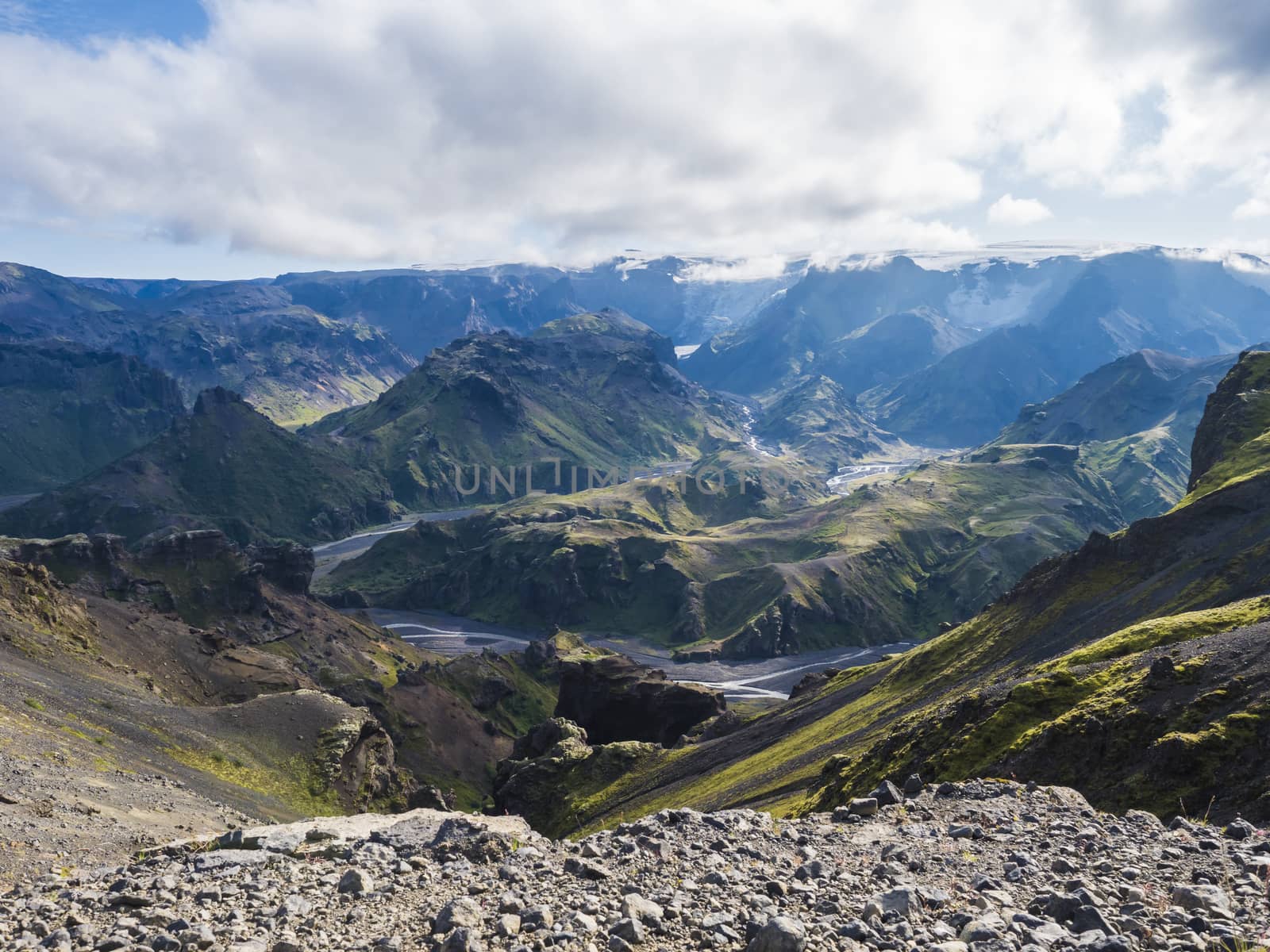 Landscape of Godland and thorsmork with rugged green moss covered rocks and hills, bending river canyon, Iceland, Fimmvorduhals hiking trail. Summer blue sky white clouds.