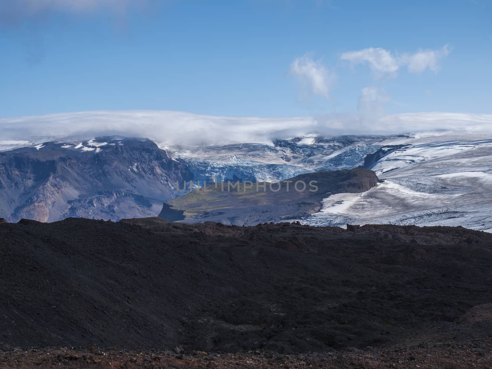 View over a landscape of Godland and thorsmork with the Eyjafjallajokull glacier and volcano, lava formations, snow, ice and green moss. Iceland, Fimmvorduhals hiking trek. Summer cloudy day.