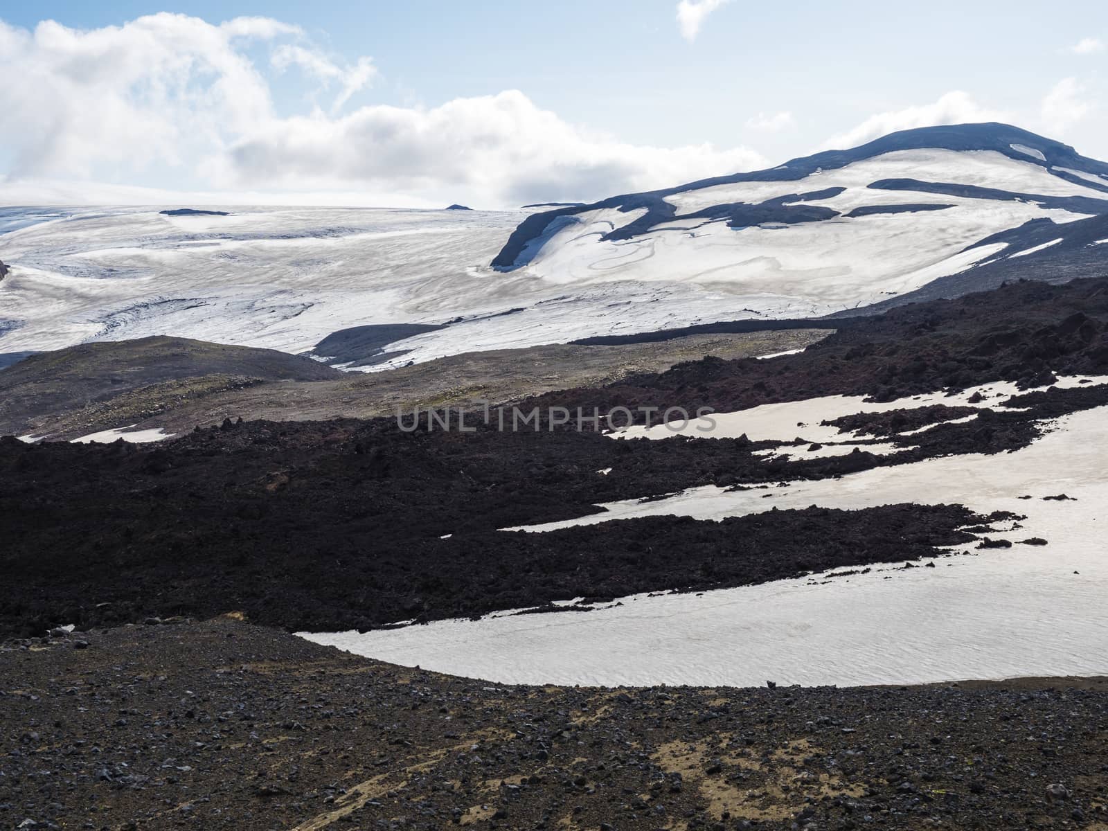 View over a landscape of Godland and thorsmork with the Eyjafjallajokull glacier and volcano, lava formations, snow, ice and green moss. Iceland, Fimmvorduhals hiking trek. Summer cloudy day.