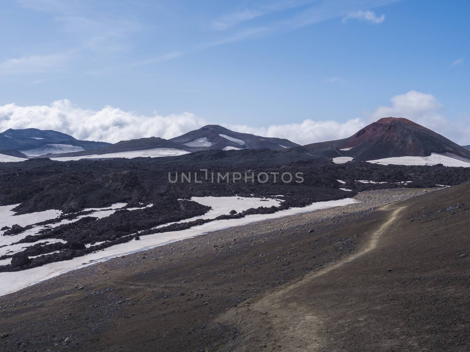 Red and black volcanic Iceland landscape at Fimmvorduhals hiking trail with glacier volcano lava field, snow and magni and mudi hill, createed by eruption of Eyjafjallajokull in 2010 which affected air traffic in the whole Europe. Summer blue sky.