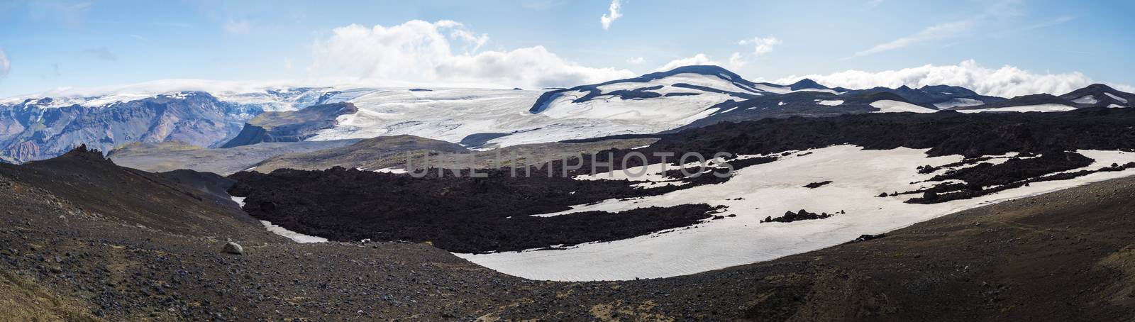 Panoramic view on Red and black volcanic Iceland landscape at Fimmvorduhals hiking trail with glacier volcano lava field, snow and magni and mudi hill, createed by eruption of Eyjafjallajokull in 2010 which affected air traffic in the whole Europe. Summer blue sky.