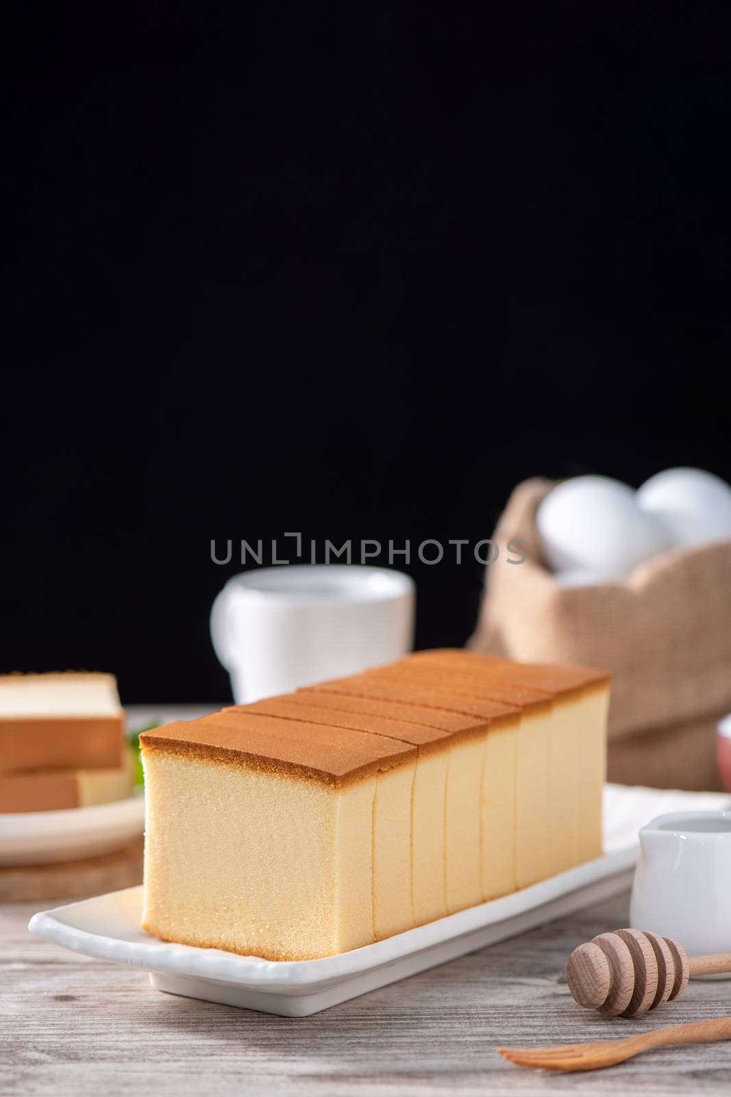 Castella (kasutera) - Delicious Japanese sliced sponge cake food on white plate over rustic wooden table, close up, healthy eating, copy space design.
