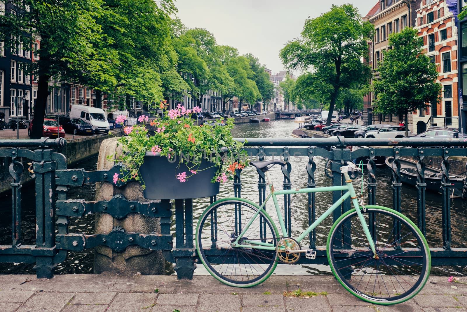 Typical Amsterdam view - Amsterdam canal with boats and parked bicycles on a bridge with flowers. Amsterdam, Netherlands