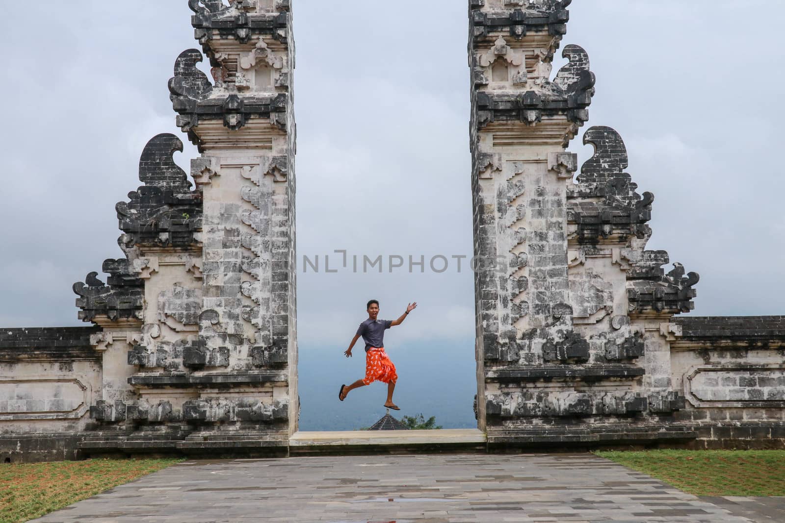 Bali, Indonesia. Young taveler man jumping with energy and happiness in the gate of heaven. Lempuyang temple.