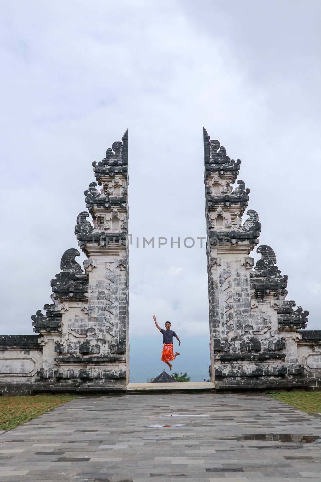 Bali, Indonesia. Young taveler man jumping with energy and happiness in the gate of heaven. Lempuyang temple.