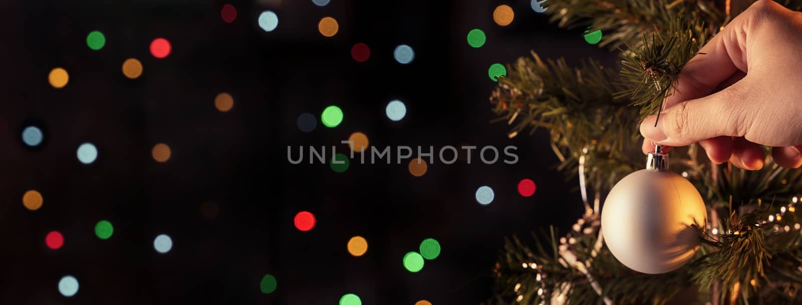 Christmas background concept- beautiful decor bauble hanging on the Christmas tree with sparkling light spot, blurry dark black background, copy space, close up.