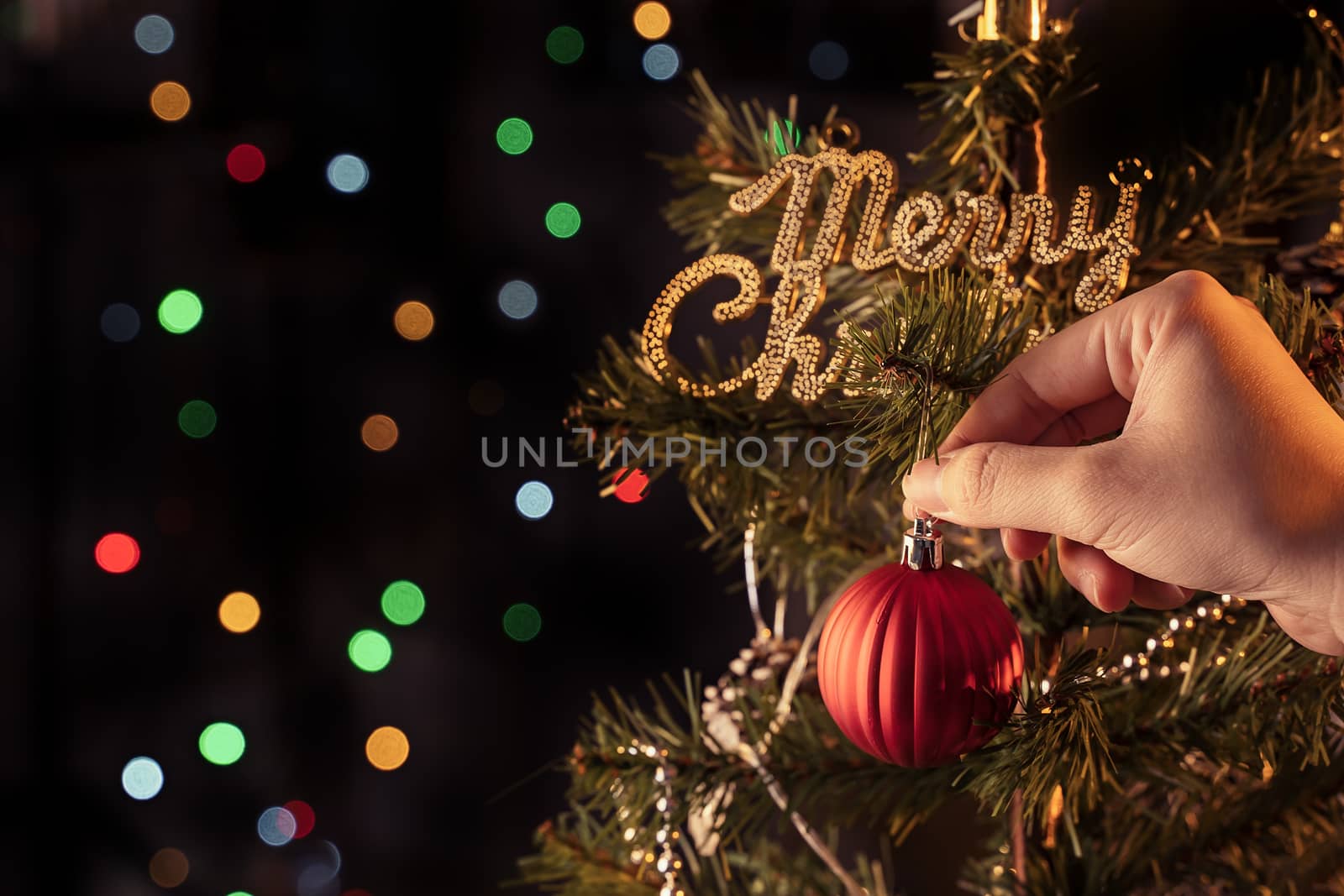 Christmas background concept- beautiful decor bauble hanging on the Christmas tree with sparkling light spot, blurry dark black background, copy space, close up.