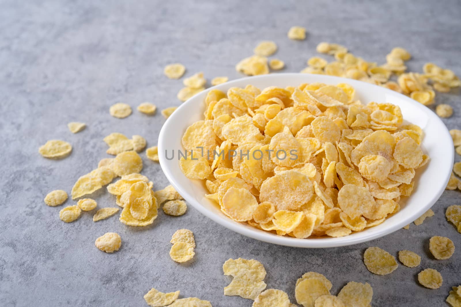 Corn flakes bowl sweeties with milk on gray cement background, c by ROMIXIMAGE