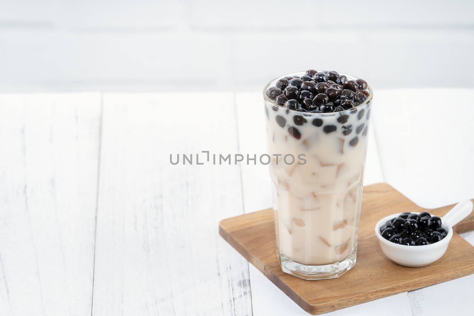 Bubble milk tea with tapioca pearl topping, famous Taiwanese drink on white wooden table background in drinking glass, close up, copy space