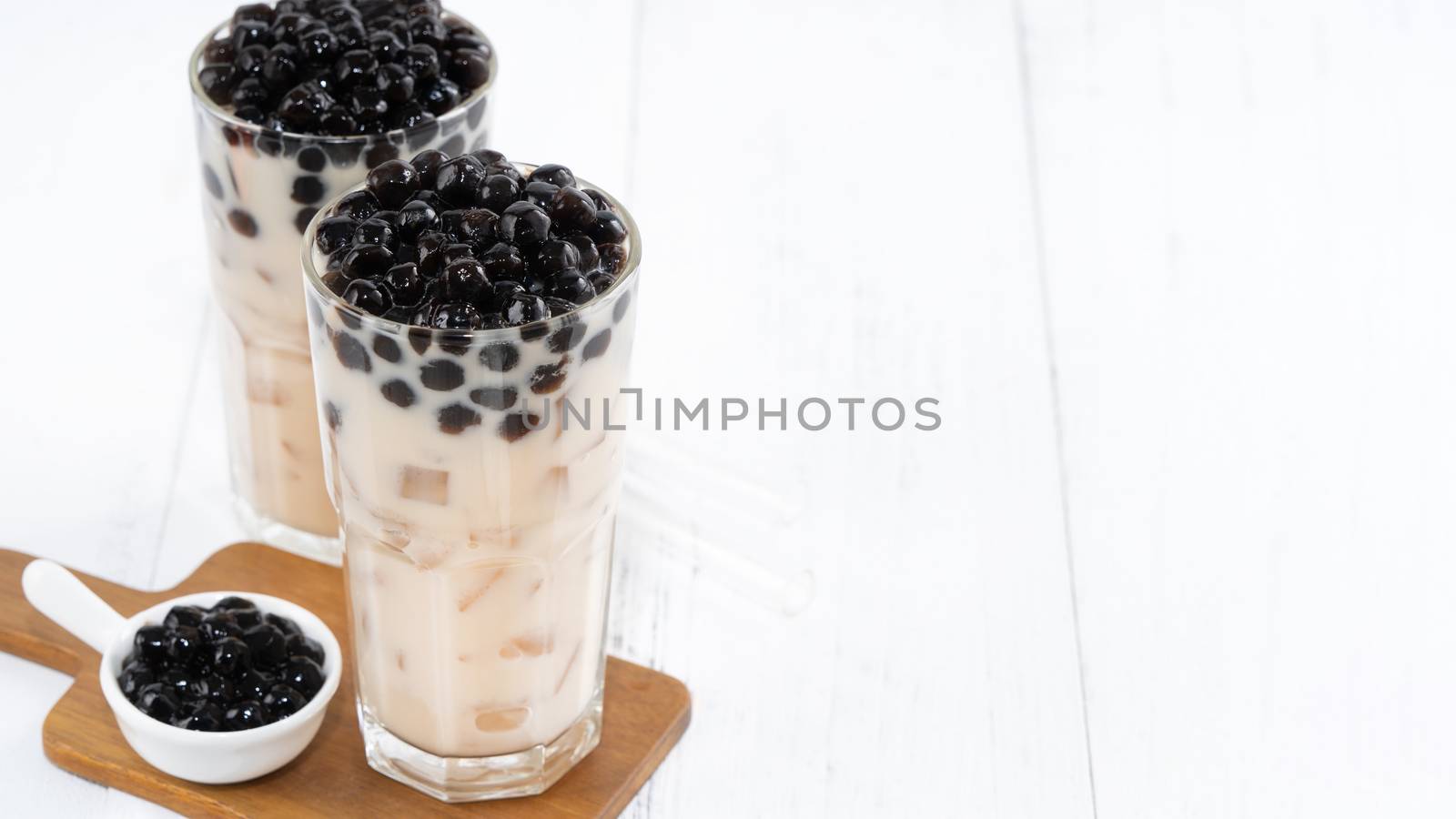 Bubble milk tea with tapioca pearl topping, famous Taiwanese drink on white wooden table background in drinking glass, close up, copy space