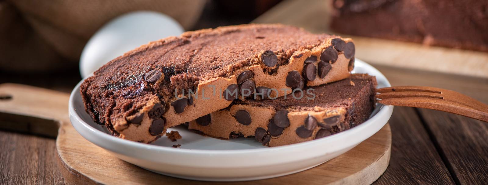 Chocolate flavor Taiwanese traditional sponge cake (Taiwanese castella kasutera) on a wooden tray background table with ingredients, close up.