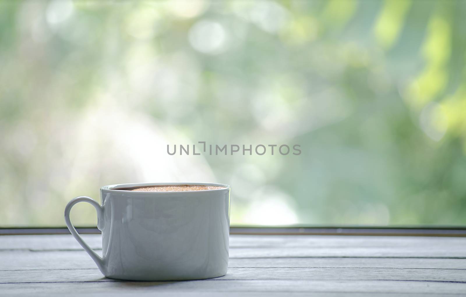 Hot coffee cup with white the wooden table and the Green leaf background with copy space on right