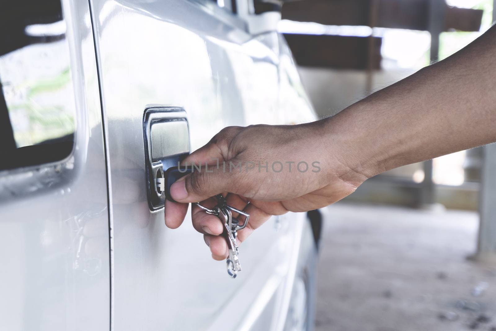 Normal Car key in men hand opening his car by yodsawai