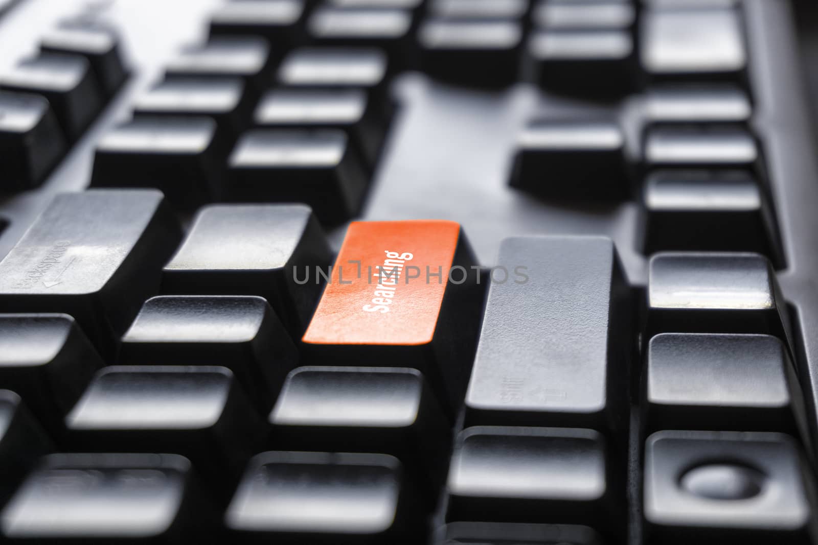 The concept of the orange button on the computer that is design to enter a searching key font on a black PC keyboard for office the internet or work. by yodsawai