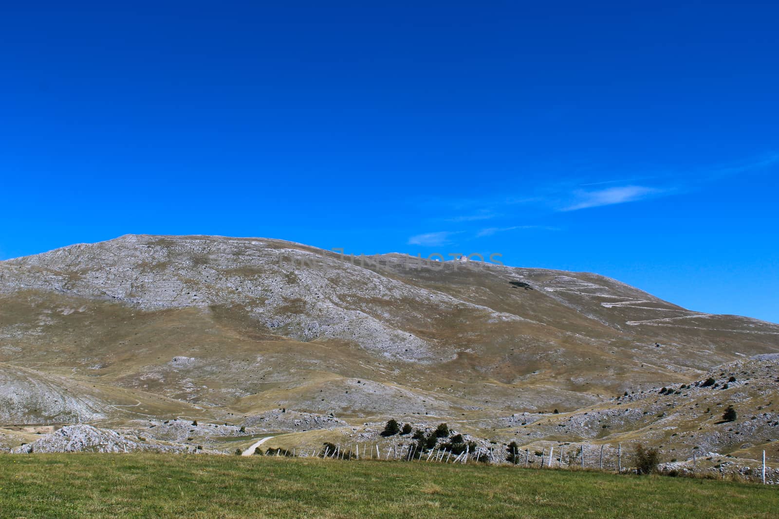 A meadow with a downed fence at the end of the meadow. In the background, mountain desolation. On the way to the mountain Bjelasnica, Bosnia and Herzegovina.