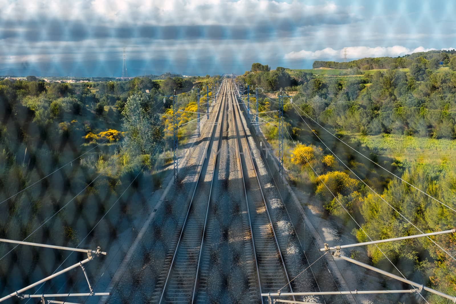 Train tracks located between the mountains, seen from the bridge through the gate. Depth and path concept.