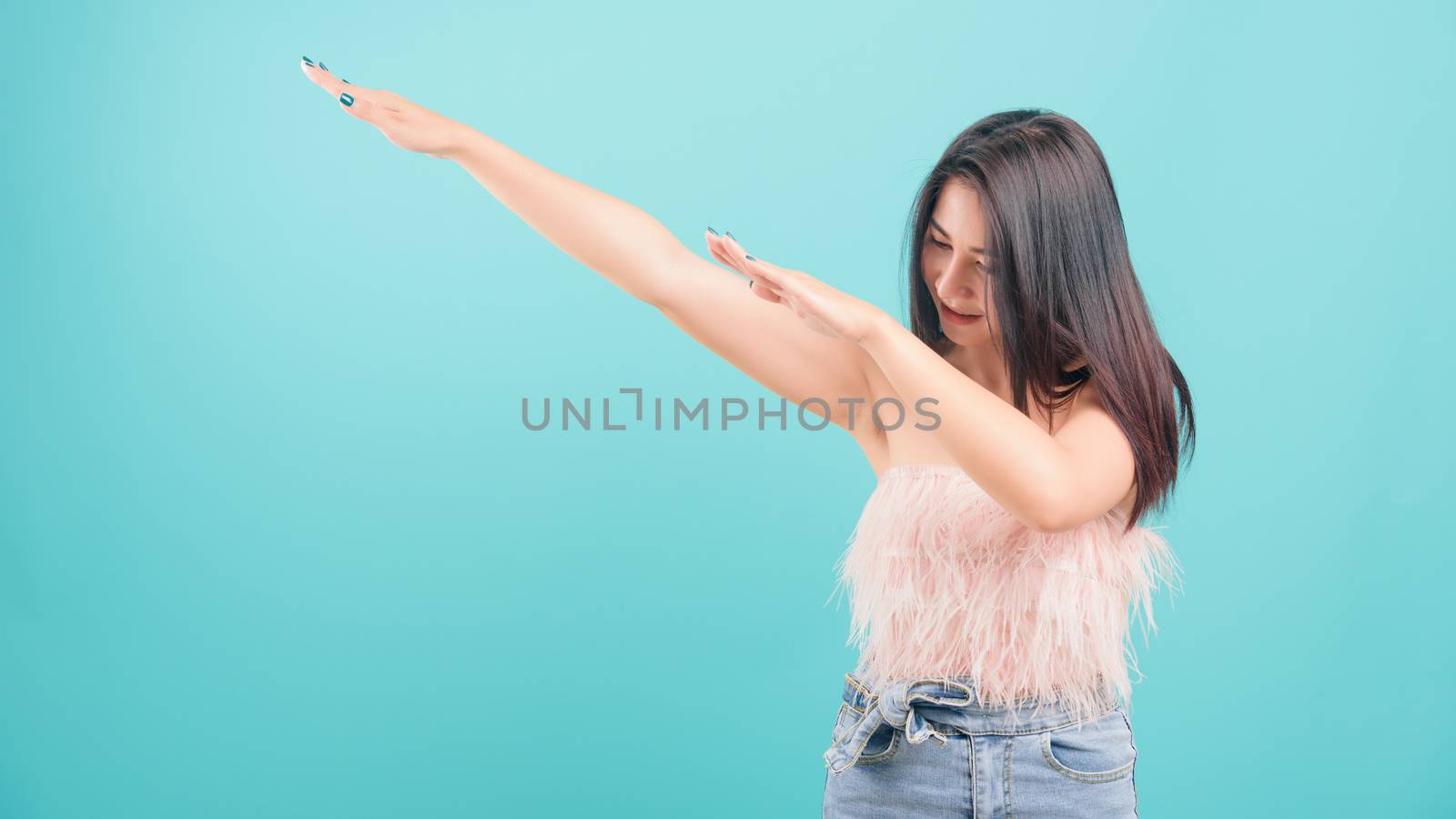 Asian happy portrait beautiful young woman standing smiling exercise Showing DAB dance gesture and looking to side isolated on blue background with copy space for text