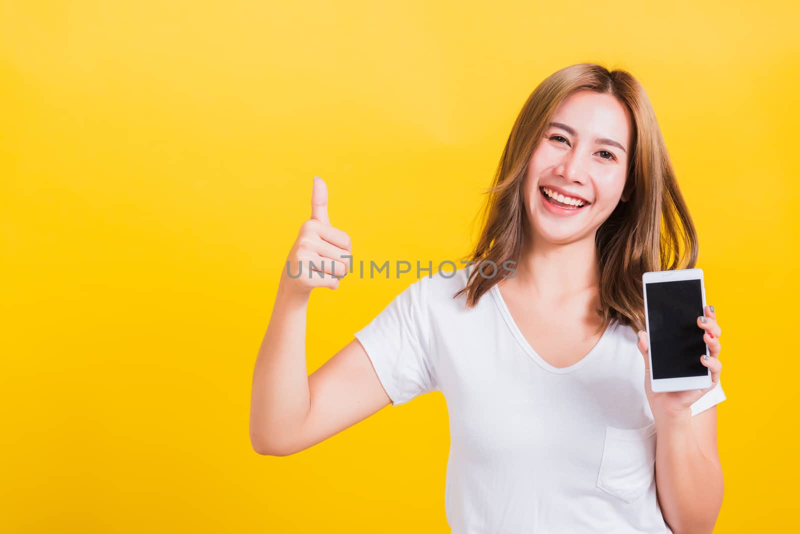 young woman standing smile, holding blank screen mobile phone by Sorapop