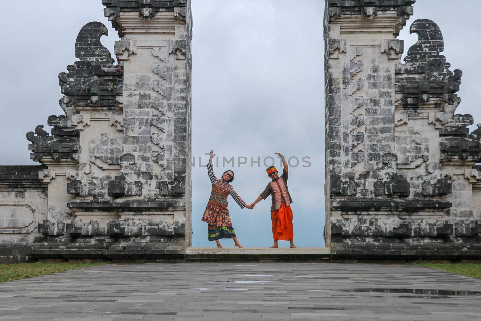 Happy young couple staying in temple gates of heaven and holding hands of each other. Perfect Honeymoon concept. Lempuyang Luhur temple in Bali, Indonesia.