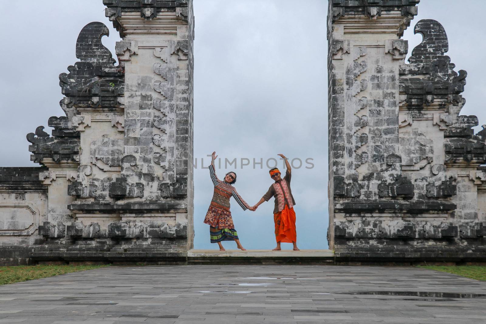 Happy young couple staying in temple gates of heaven and holding hands of each other. Perfect Honeymoon concept. Lempuyang Luhur temple in Bali, Indonesia by Sanatana2008