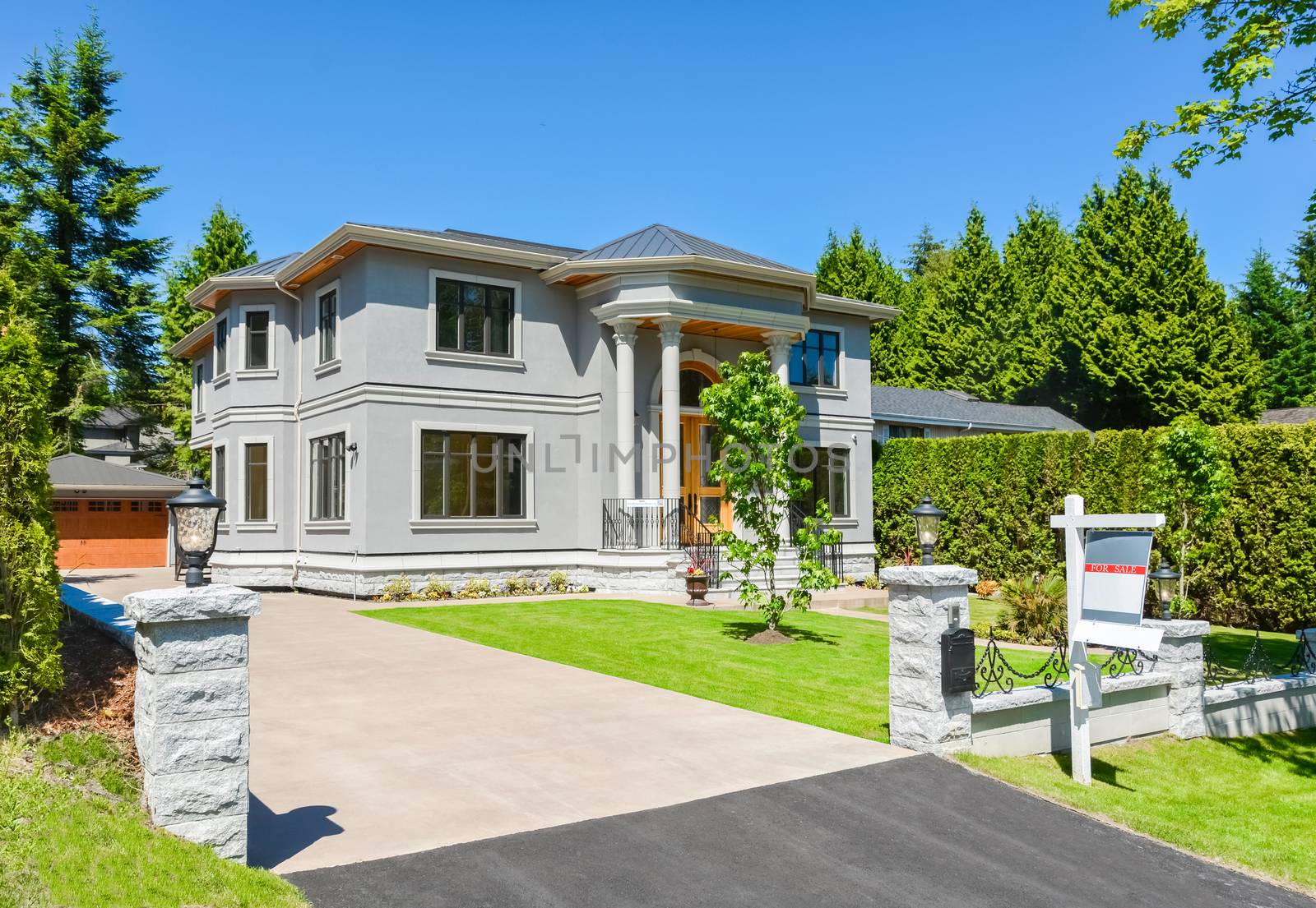 A perfect neighbourhood. Luxury family house with concrete driveway and garage on back yard on blue sky background