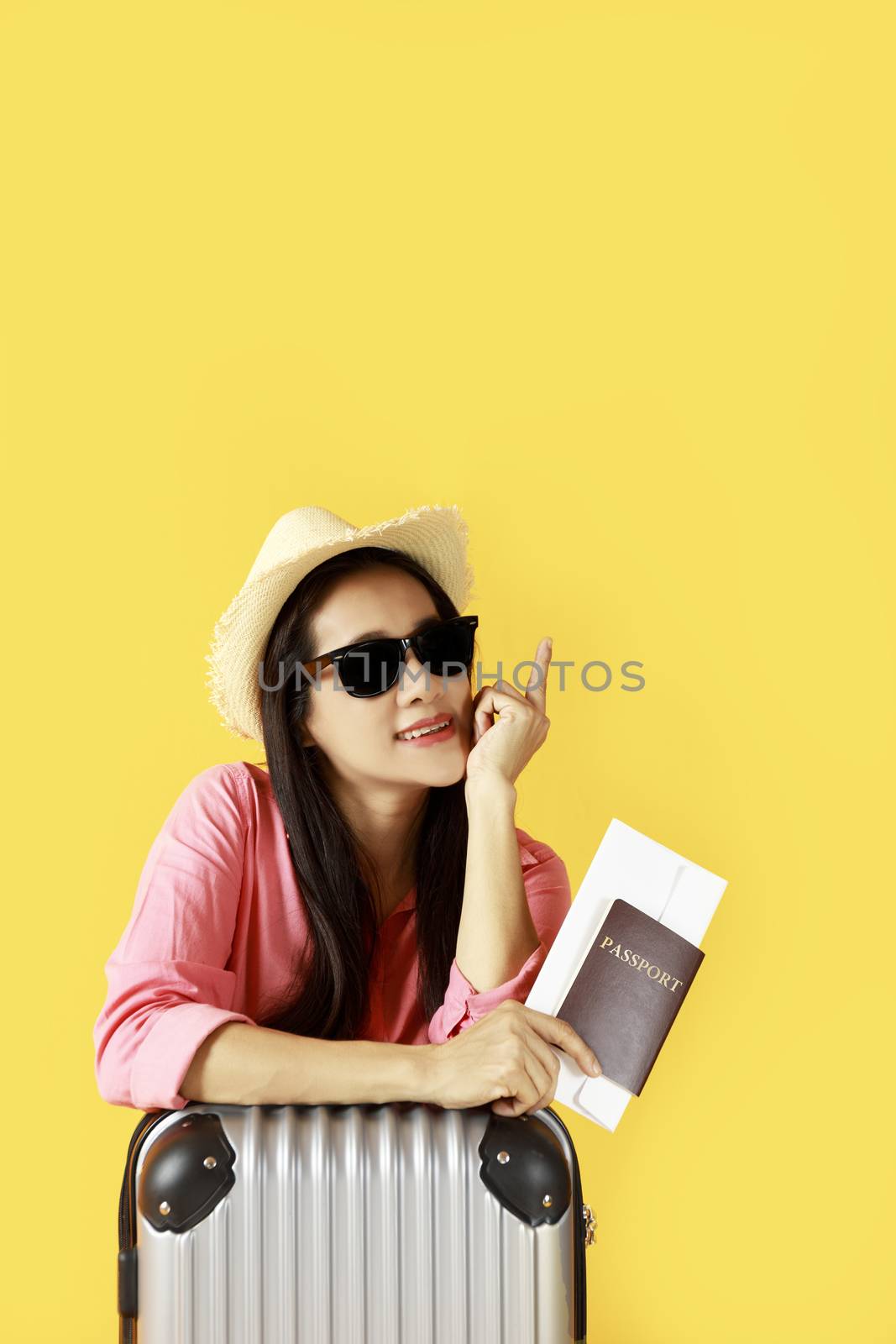 Asian women long hair wear Straw hat, sunglasses in hand holding passport book and travel bag with copy space banner. Young girl ready to travel with suitcase and passport on yellow background. Summer