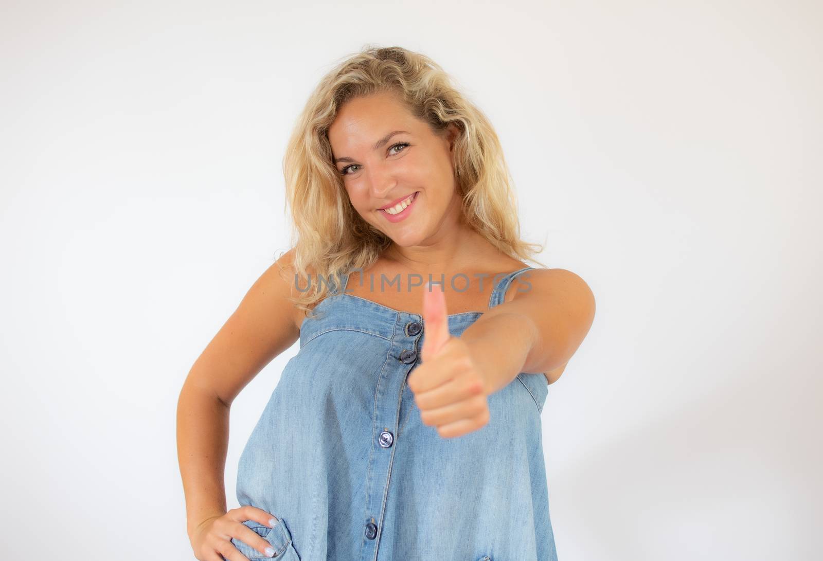 Pretty blonde woman in blue dress smiling making finger up gesture