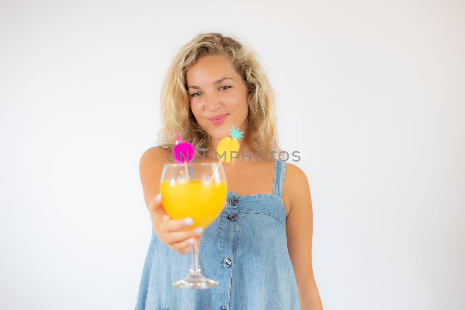 Pretty blonde woman in blue dress smiling with a fruit cocktail