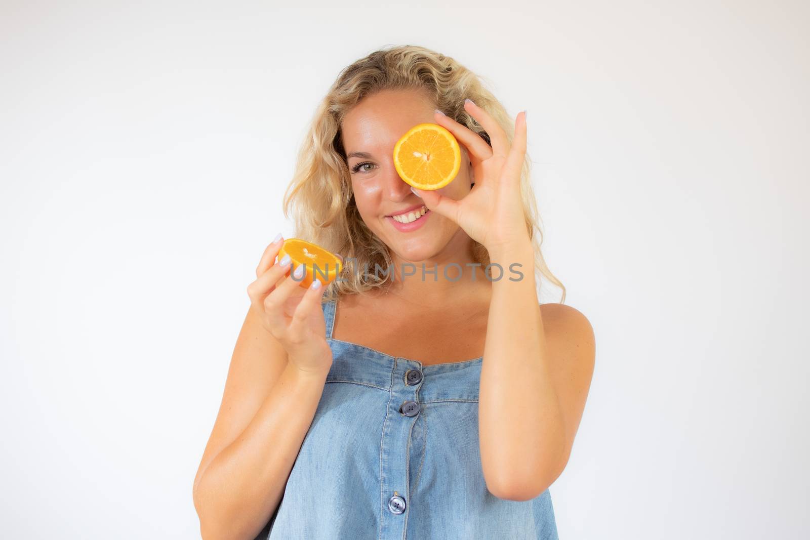 Pretty blonde woman in blue dress smiling with an orange in the eye