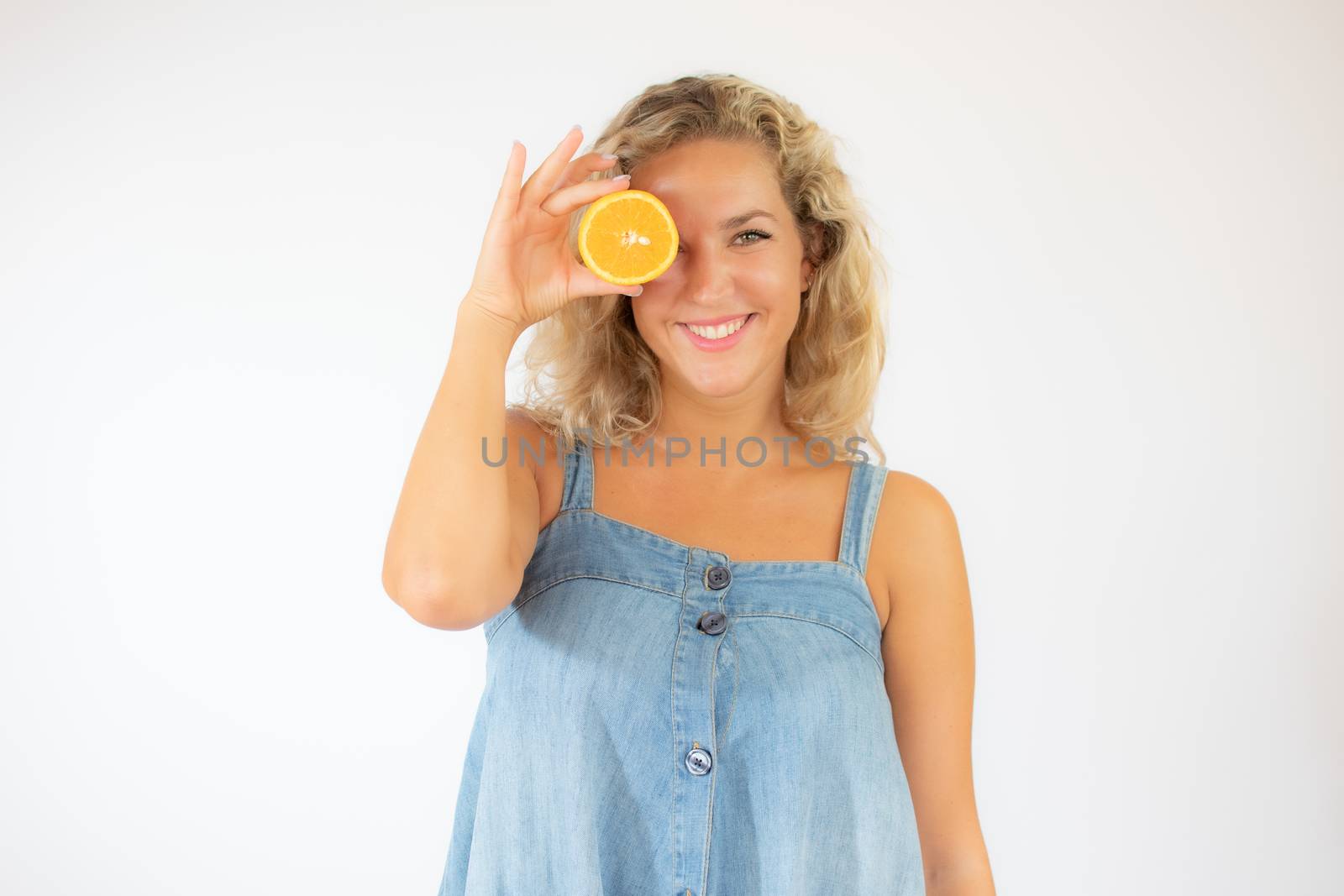 Pretty blonde woman in blue dress smiling with an orange in the eye