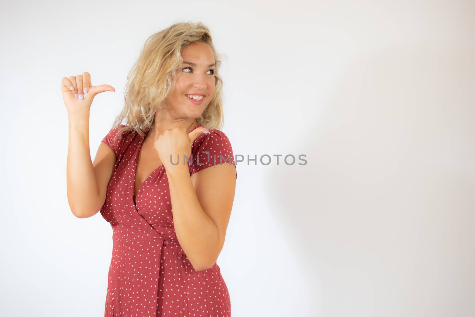 Beautiful smiling blonde woman in a red dress pointing something