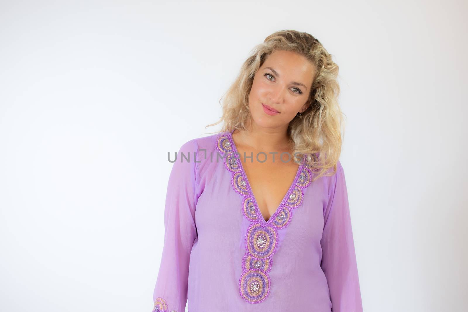 Pretty blonde woman in lila caftan smiling on white background